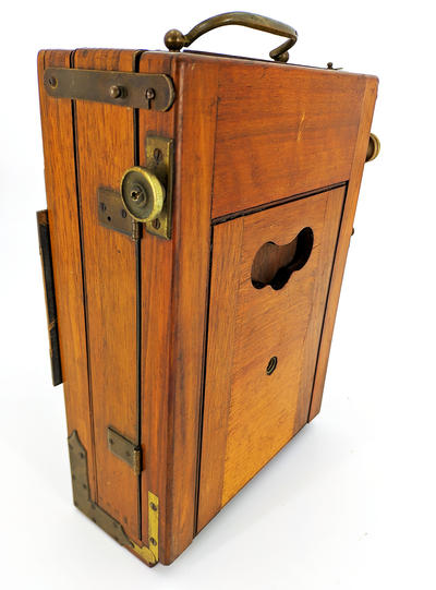 Фотокамера со штативом. Одна из ранних студийных фотокамер. На объективе ещё отсутствует механический затвор с выдержкой съемки.