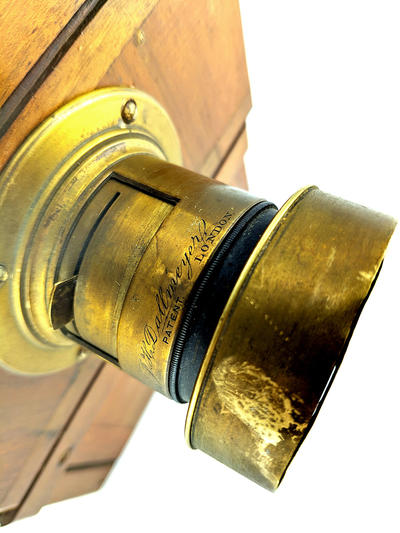 Фотокамера со штативом. Одна из ранних студийных фотокамер. На объективе ещё отсутствует механический затвор с выдержкой съемки.